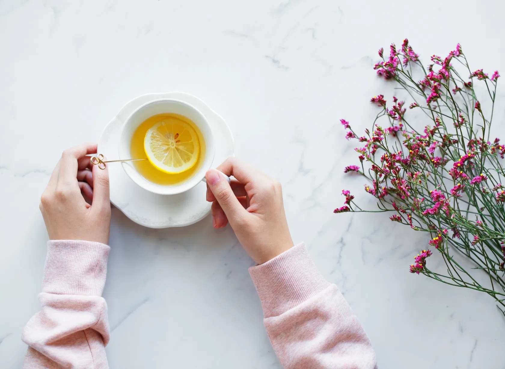Frau hält Tasse mit Zitronentee auf Marmoruntergrund